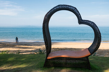 Fototapeta premium Heart shaped chair with blur couple on beach