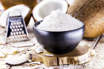 clay bowl with grated coconut, with open coconut in the background