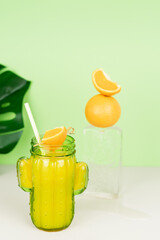 Orange juice in a cactus-shaped glass with ice and orange decoration.