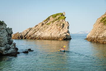 Woman and man kayaking on crystal clear water surrounded by nature in a sunny summer day