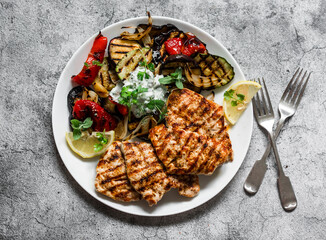 Delicious tapas barbecue plate - grilled turkey, eggplant, zucchini pepper with tzatziki sauce on a gray background, top view
