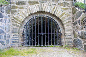 Medieval stone arch leading into a tunnel. Locked black iron gate. Part of defences of old Gothenburg, Sweden.