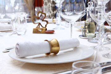 Festive table setting.Napkins made of cotton with brass rings. The concept of holidays.Wine glasses on the table. White plates. VIP lounge.Top view. White tablecloth with a textured pattern. Out of