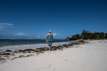 woman in a blue hat posing against the backdrop of corals and islands during low tide of the sea