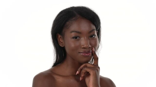 Portrait of a pretty African woman, with her finger by her mouth, squinting with a thinking expression. White background.