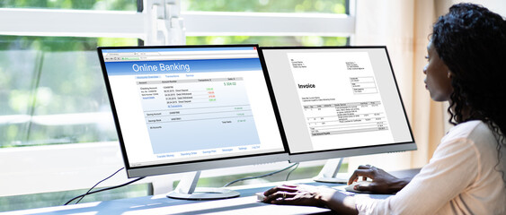 Looking At Invoice While Doing Online Banking On Computer