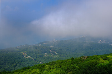 View of mountains and forest in the fog mist, landscape of mountain Akhun hills with radio towers and a Ferris wheel in the morning haze with noise film grain effect, soft selective focus