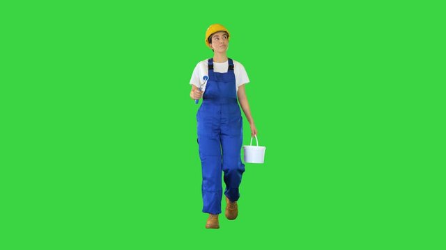Female house painter with paint brush walking looking what to paint on a Green Screen, Chroma Key.