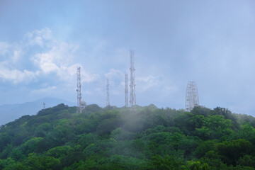 Obraz premium View of mountains and forest in the fog mist, landscape of mountain Akhun hills with radio towers and a Ferris wheel in the morning haze with noise film grain effect, soft selective focus
