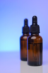 Cosmetic Mockup . Face serums in brown glass bottles in blue light.copy space. Organic natural oils. Serum for face skin. Natural bio cosmetics concept.Two glass brown bottles on a blue background.