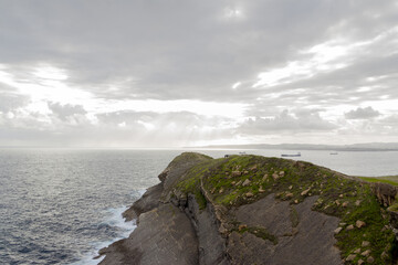 Sunset on a cliff in front of the sea on a cloudy day.