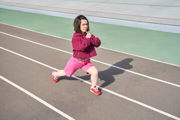 Midget woman doing stretching at the stadium at the morning