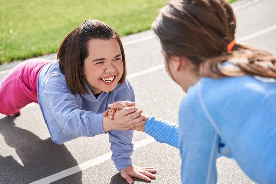 Woman laughing out loud while standing at the plank and spending time with her friend