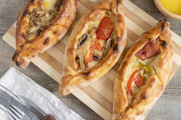Peinirli with different flavours baked and ready to serve. Greek open faced pizzas on cutting board...