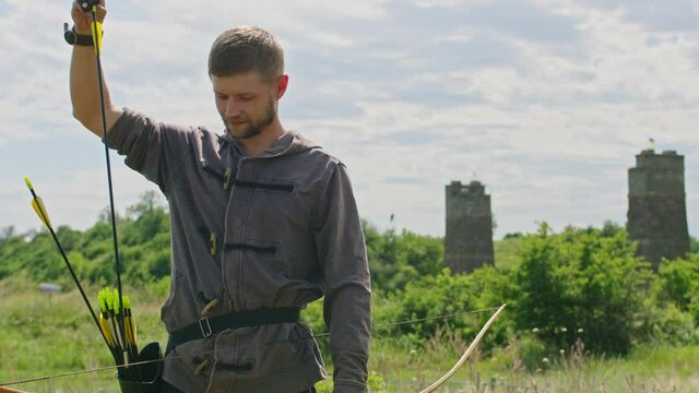 a young guy shoots a bow at a target, in nature, and hits the target, the arrow pierces the target for flight, pulls the bowstring tightly for a shot. Prores 422