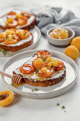 bruschetta with baked apricot, cottage cheese, thyme and honey. on white background. atmosphere of morning and breakfast