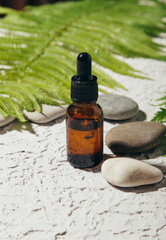Natural skincare product in glass bottle with dropper. Serum for woman facial skin. Herbal mineral cosmetic, vitamin body oil on white stand. Transparent package cosmetology with pipette. Copy space