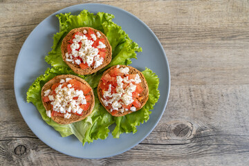 Burley rusks with chopped tomatoes and feta cheese served on lettuce leaves. Greek “Dakos”...