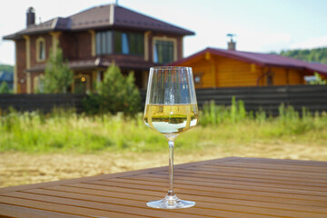 A glass of wine on a wooden table against the background of a country house.