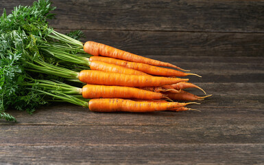 Bunch of fresh carrots on wooden table, with copy space.