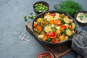 Frying pan with vegetable stew on a gray-blue background.