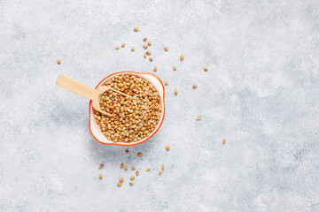 Coriander dry seeds in a wooden spoon.