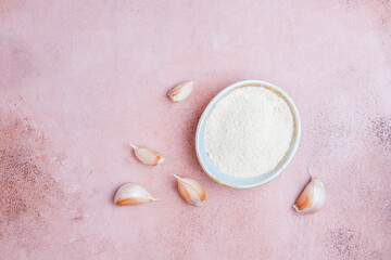 Bowl with dried garlic powder and garlic bulbs.