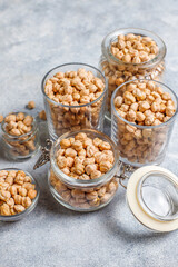 Uncooked dried chickpeas in different glass jars and bowls.