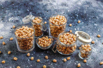 Uncooked dried chickpeas in different glass jars and bowls.