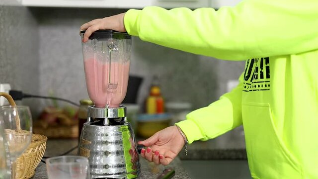 mujer licuando jugo de fresa en la cocina de su hogar 