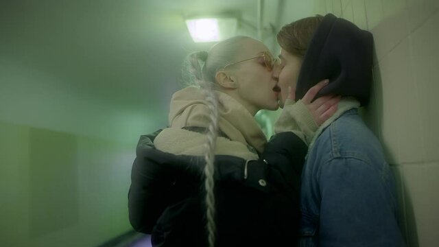 Lesbian couple of girls in love and passionately kissing on the lips of a public place of the underground passage.