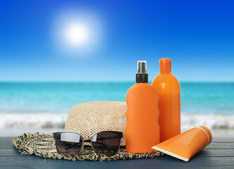 Different skin sun protection products and beach accessories on blue wooden table against seascape....