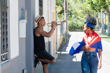 Side shot of latino man playing trumpet and latina woman looking at him: Music and diversity concept