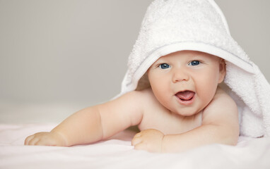 Close-up portrait of cute baby boy in white terry towel on white background. Bathing babies and...