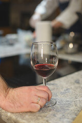 Man holds a glass of red wine while partying in a cafe or restaurant. 
