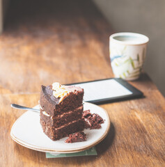 A table with a cup of coffee, a cake, and an e-reader
