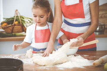 Happy woman and her daughter are kneading the dough and baking cookies for a delicious family feasting. Christmas, New year, Thanksgiving, Anniversary, Mothers Day. Healthy meal cooking concept