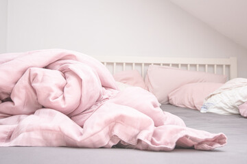 Fototapeta na wymiar Pink blankets on a grey and white bed.