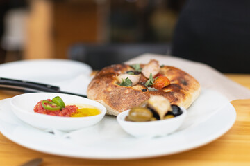 Italian focaccia with cherry tomatoes, thassos olives, oregano, olive oil and sea salt. served with salsa and olives