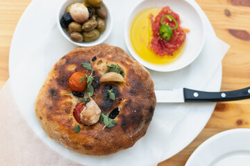 Italian focaccia with cherry tomatoes, thassos olives, oregano, olive oil and sea salt. served with salsa and olives