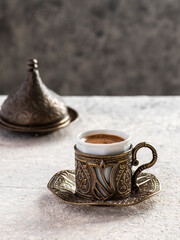 Turkish coffee in traditional copper cup on gray background.