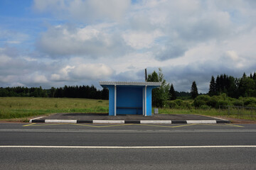 Empty bus stop in the countryside on a sunny summer day. transport stop in a picturesque place. Lockdown concept. Bus stop without passengers. Stop without billboard