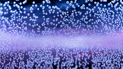 Tiny floating air bubbles abstract under water purple and blue background. Macro air bubbles underwater wallpaper