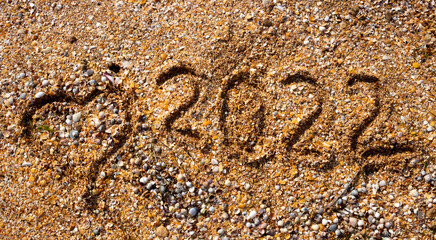 Fototapeta na wymiar The numbers 2022 and the heart on the wet sand. The concept of the New Year 2022. Summer holidays and sea trips