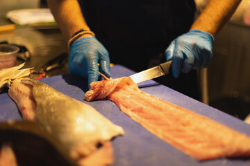 the chef cuts the fish in blue gloves