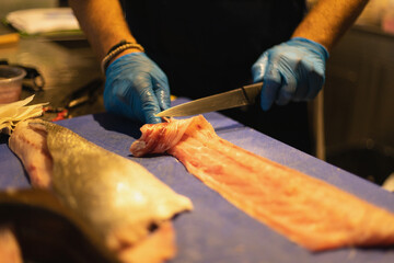 the chef cuts the fish in blue gloves