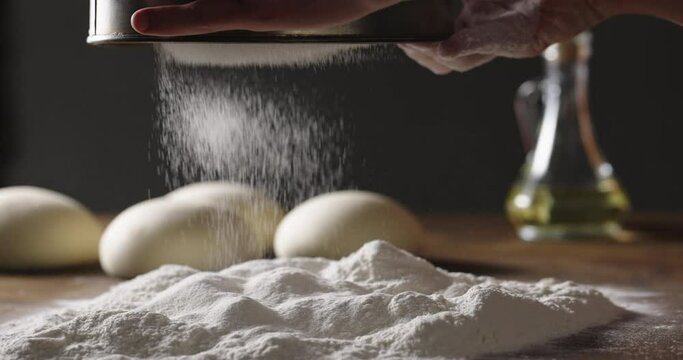 Close up shot of sifting white flour onto wooden table with a sieve. Preparation for making bread in bakery. Food and drink, healthy food 4k footage