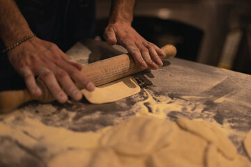 the cook rolls out the dough with a rolling pin. Table in flour