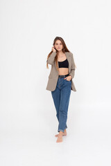 portrait of young caucasian attractive woman with long brown hair in blue jeans, black top and suit jacket on white background. skinny pretty lady posing at studio with bare feet