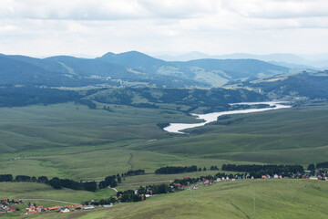 View from the mountain on the green fields and hills in the distance.  Green nature. Nature wallpaper. Mountain landscape. Mountain panorama. 